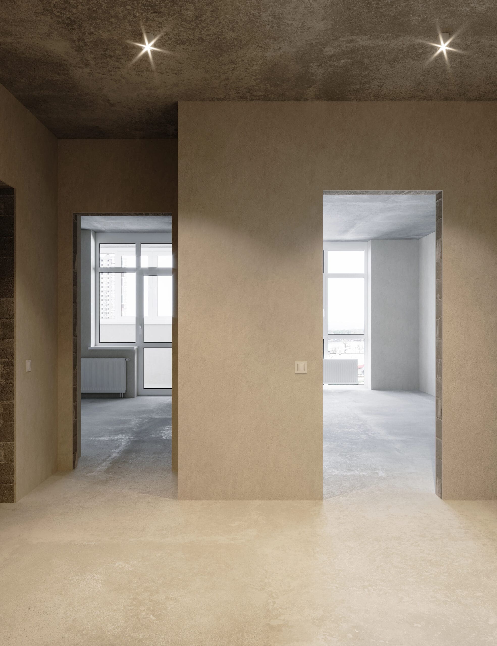 The minimalist interior of this concrete apartment boasts bare walls and floors, with two open doorways leading to rooms where large windows pour in natural light. The space is elegantly illuminated by recessed lighting, seamlessly integrated with suspended ceilings for a sleek touch.